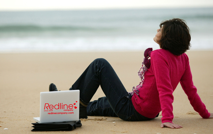 Woman on beach with laptop - Redline Company