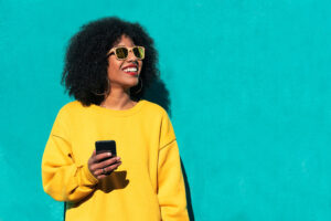 Woman with yellow sweater holding a phone created by Redline Company